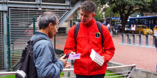 Foto de u funciionario entregando un libro a un ciudadano 