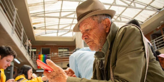 Un adulto mayor en Bogotá, revisando su celular.