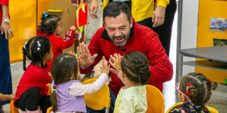 El alcalde Carlos Fernando Galán sonriendo con unos niños y niñas de un jardín infantil.