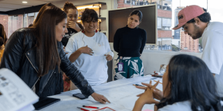 Mujeres y hombres reunidas trabajando en una mesa.