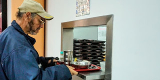 Un adulto mayor recibiendo alimentación en un comedor comunitario