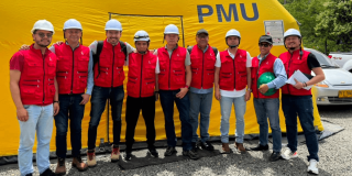 Foto que muestra un grupo de personas con chaleco rojo y casco blanco sonriendo 