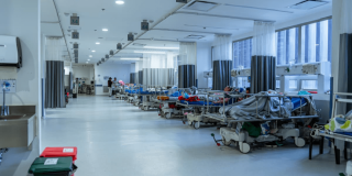 Foto que muestra la sala de urgencias de un hospital, con varios pacientes recibiendo atención en las camillas de la sala.