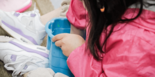 Niña jugando en el piso con un balde.