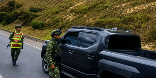 Uniformados del Ejército acercándose a una camioneta negra en una carretera.