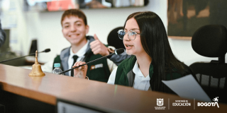 Dos estudiantes hablando por un micrófono 