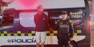 Hombre capturado junto a un policía y una patrulla.