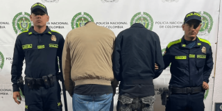 Dos 'rompevidrios' capturados, de espaldas en medio de dos Policías.