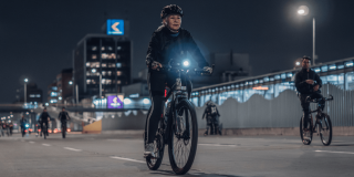 Mujer transita en bicicleta en calle de Bogotá durante Ciclovía Nocturna.