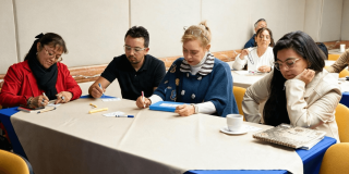 Foto que muestra personas sentadas escribiendo en un escritorio 