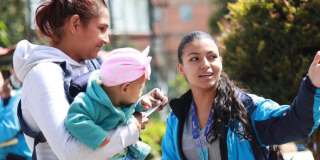 Foto de una funcionaria orientando a una madre con su bebe 