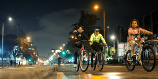 Tres personas recorren una vía durante la Ciclovía Nocturna en Bogotá.
