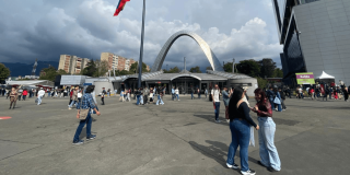 Vista exterior de Corferias en Bogotá con personas transitando por la plaza principal, el arco de acceso al centro de eventos.