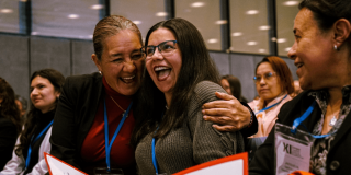 Mujeres sonriendo y abrazándose en un encuentro en Bogotá.