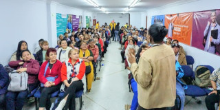 Adultos mayores y jóvenes reunidos en un salón conversando 