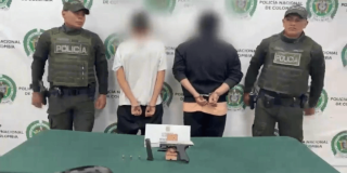 Dos hombres capturados, en medio de dos policías.