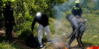 Foto que muestra dos policías y dos personas apagando una fogata 