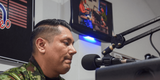 Uniformado del ejército hablando en una cabina de radio.