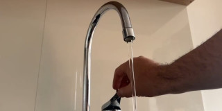 Una persona abriendo una llave de agua en una vivienda en Bogotá.