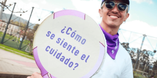 Hombre sosteniendo una pancarta que dice "¿Cómo se siente el cuidado?".