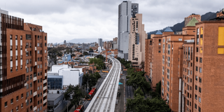 Vista de un tramo elevado de la Línea 1 del Metro de Bogotá en construcción, rodeado de edificios residenciales y de oficinas.