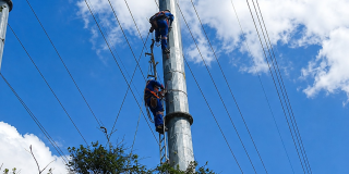 Foto que muestra a un operario de la empresa de energía haciendo una reparación en un poste de luz.
