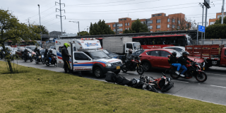 Ambulancia detenida sobre una vía de Bogotá junto a dos motocicletas caídas en el carril.