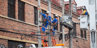 Foto que muestra dos personas con uniforme de Enel Colombia en un poste de luz