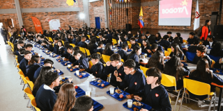 Foto que muestra estudiantes sentados dentro de un comedor escolar 