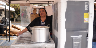 Mujer con una nevera y una olla, para apoyo a su emprendimiento en Bogotá.