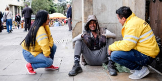 Dos funcionarios de la Secretaría de Integración Social conversando con un habitante de calle. 