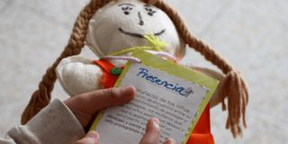 Manos de niña sosteniendo una muñeca de trapo.