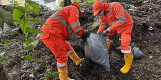 Foto que muestra dos personas con el uniforme de Aguas Bogotá levantando residuos de la calle