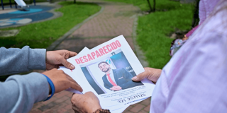Personas sosteniendo un cartel de persona desaparecida. 