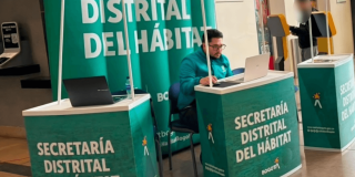 Foto que muestra un señor con un computador y avisos con el texto Secretaría Distrital del Hábitat
