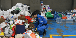 Foto que muestra una persona organizando elementos como alimentos, papel higienico y cajas