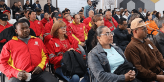 Personas sentadas en filas de sillas durante un encuentro ciudadano en un auditorio.