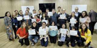 Foto que muestra un grupo de personas sonriendo con diplomas en las manos