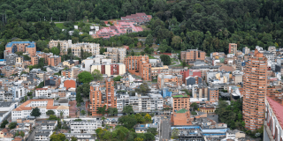 Vista panorámica de Bogotá con edificios residenciales y comerciales de diferentes alturas en primer plano.