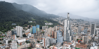Vista panorámica de Bogotá con edificios residenciales y comerciales de diferentes alturas en primer plano, y los Cerros Orientales en un día nublado.