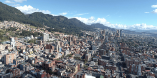 Vista panorámica de Bogotá con edificaciones, corredores viales y cerros orientales bajo cielo despejado.