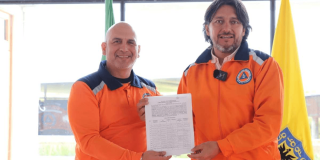 Foto que muestra dos personas sonriendo con un documento en la mano