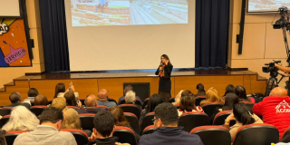 Foto de una mujer hablando en un auditorio 