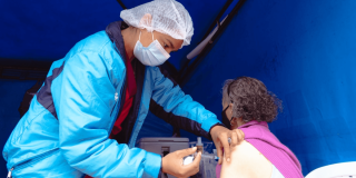 Foto que muestra un enfermero colocando una vacuna en un brazo de una mujer
