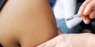 Foto que muestran unas manos colocando una vacuna en un brazo 
