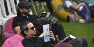 Imagen de hombres sentados en sillones al aire libre con libros abiertos.