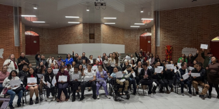Grupo de personas posando para la foto de grado del programa de formación, mostrando sus diplomas.