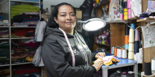 Foto de una mujer en su negocio de textiles en Bogotá.