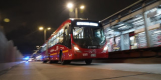 Foto de una estación y un bus de TransMilenio con iluminación de alumbrado público en Bogotá.