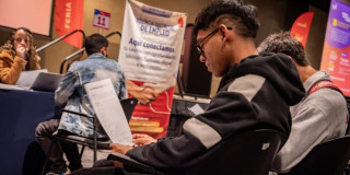 Joven con su hoja de vida en una feria de empleo en Bogotá